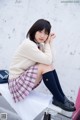 A young woman sitting on a bench with her legs crossed.