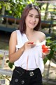 A woman in a white shirt holding a red lollipop.