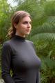 A woman in a black turtle neck top standing in front of a palm tree.