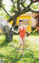 A woman in a red bathing suit is playing with a hula hoop.